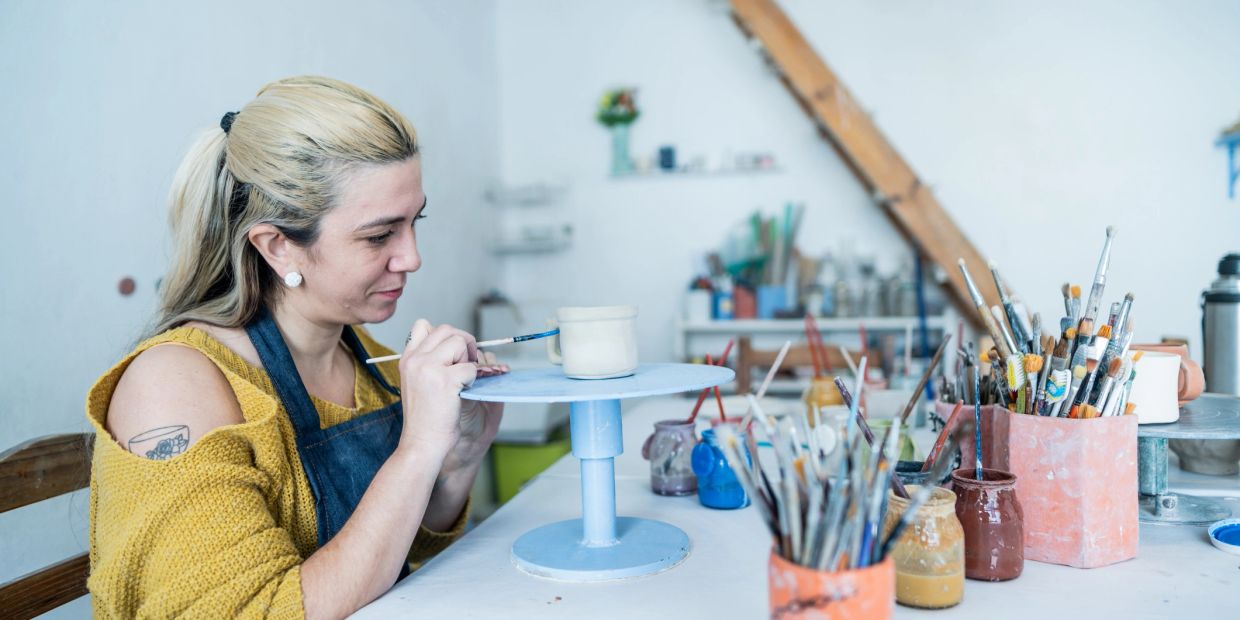 Woman painting pottery in a studio.