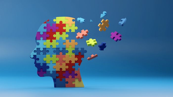 Colorful puzzle pieces forming a human head with some pieces floating away.