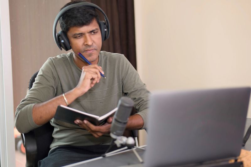 A podcaster in deep thought, planning his next episode with notes and microphone.