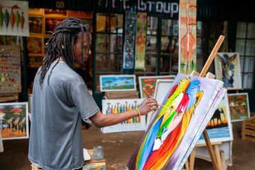 Artist painting a vibrant, colorful lion portrait in an art studio.
