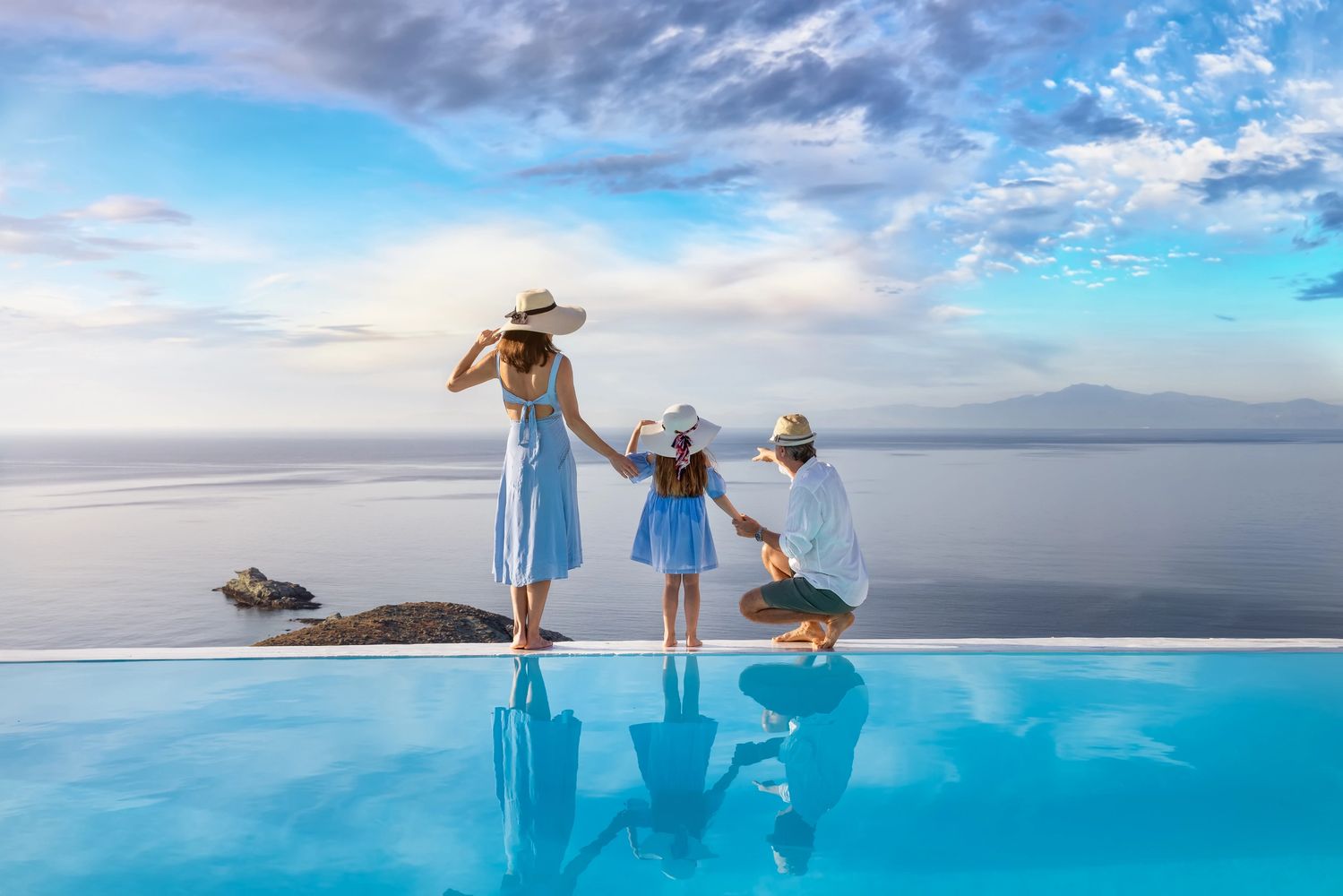 Family enjoying a scenic ocean view by the poolside at sunrise.