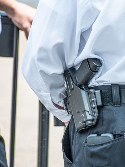 Close-up of two police officers with guns and handcuffs on their belts.