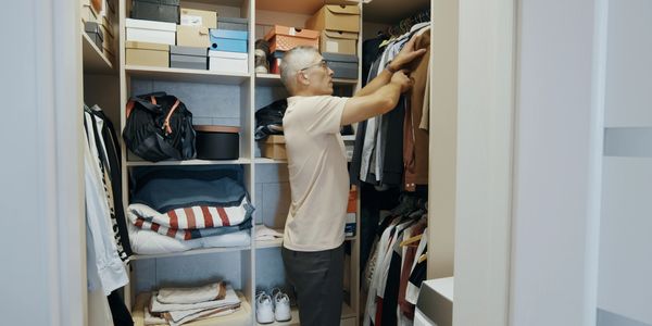 Man organizing clothes in a well-arranged closet with shelves and hangers.