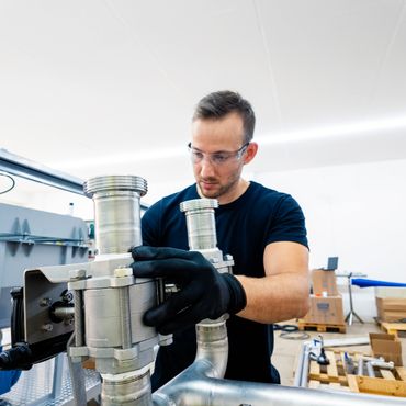 Technician assembling industrial metal pipes in a workshop.