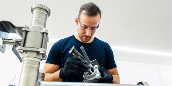 Technician assembling or repairing industrial piping with tools.