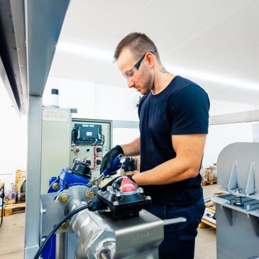 Technician working on industrial machinery in a workshop.