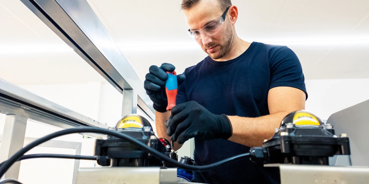 Man wearing safety glasses and gloves works with tools.