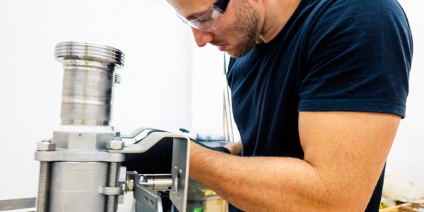 Man wearing safety goggles working on industrial equipment.