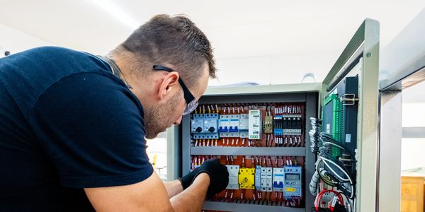 Technician inspecting and repairing an electrical control panel.