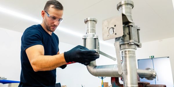 Technician assembling stainless steel pipes in a workshop.