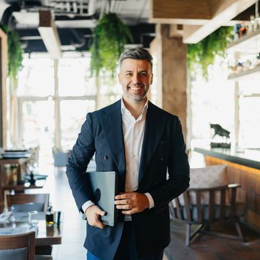 Smiling businessman holding a laptop in a modern office.