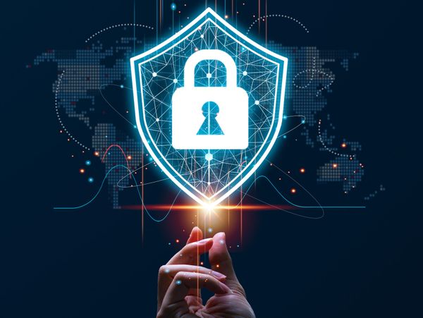 Hand holding a glowing shield with a lock symbol, representing cybersecurity.