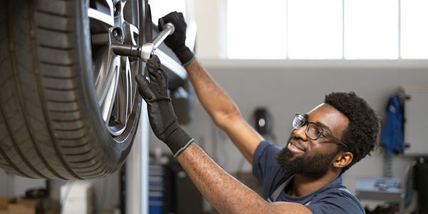 Mechanic tightening car wheel lug nuts with a wrench.