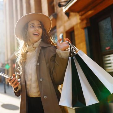 A lady smiling and holding onto several shopping bags.
