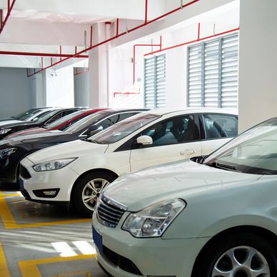 A row of cars parked in a bright indoor parking garage.