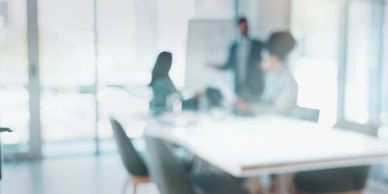 Blurred office meeting with three people around a table.