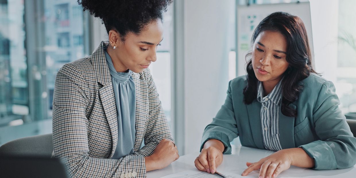 Two professional women discussing a document in a modern office.