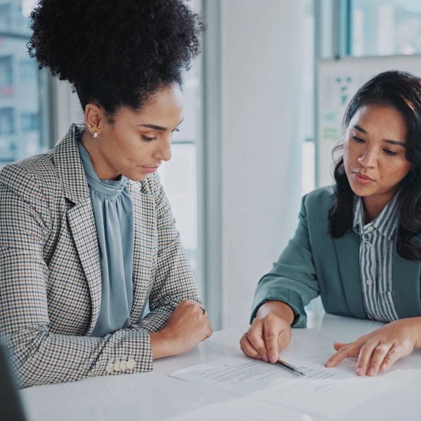 Two women collaborating over documents at a desk.