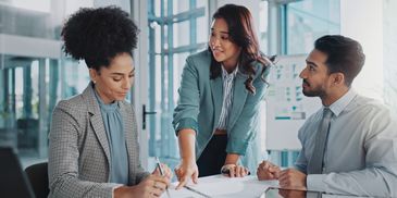 Three professionals collaborating in a modern office setting.