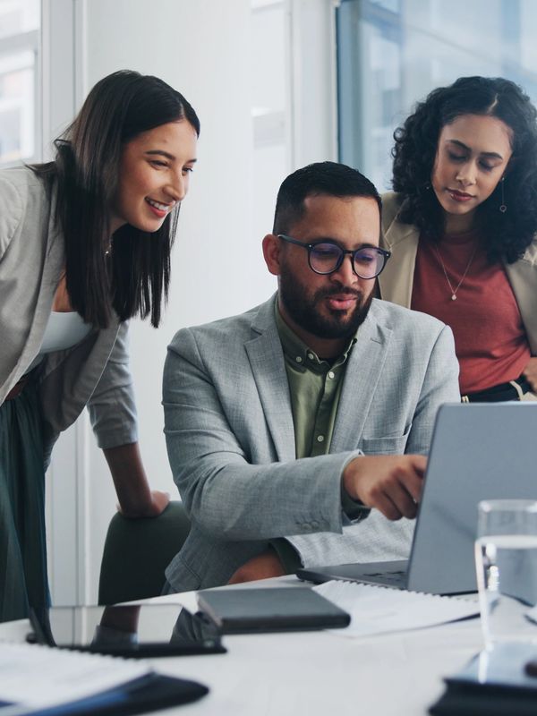 Three professionals collaborating around a laptop in a modern office.