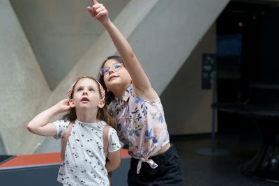 Two girls looking up, one pointing at something above.