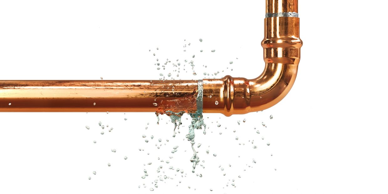Leaking water from a copper pipe joint with water droplets splashing out.