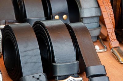 A collection of rolled and stacked men's leather belts in various colors and textures.