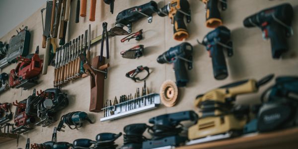 Wall with various organized power tools and hand tools.