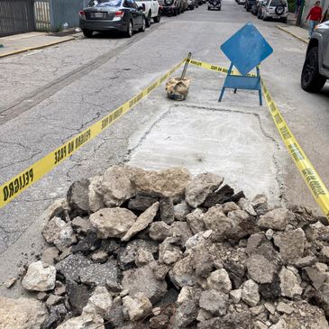 Road under repair with rubble and caution tape around.