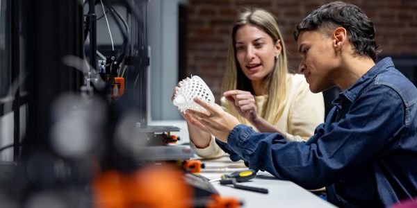 Two people examining a 3D printed object.