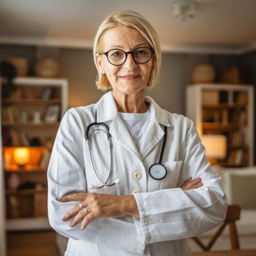 Confident female doctor in white coat with stethoscope, arms crossed, smiling.