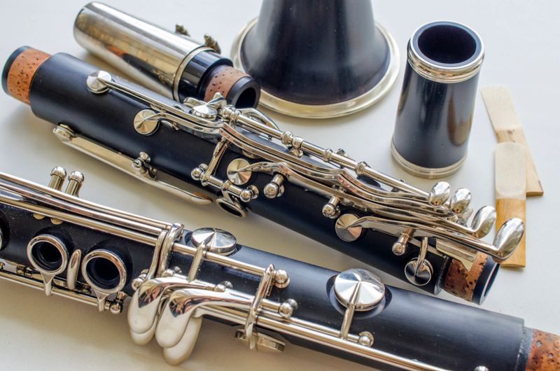 French system clarinet disassembled and two reeds on a light background