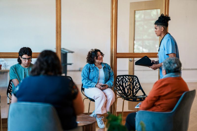 A male nurse of Peruvian descent walks into the waiting room of a hospital to retrieve his patient before an appointment.