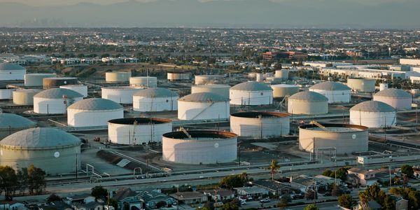 A large industrial oil storage facility with multiple white tanks.