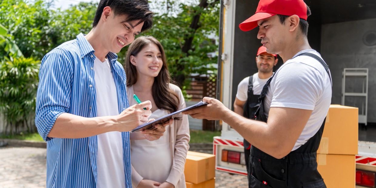 Couple signing for a delivery with happy delivery workers.