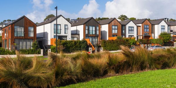 Modern townhouses with mixed wood and white siding under a blue sky.
