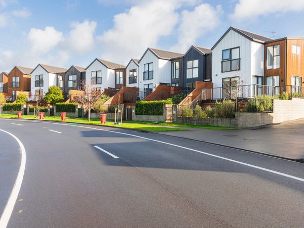 Modern townhouses with wood and white paneling along a curved street.