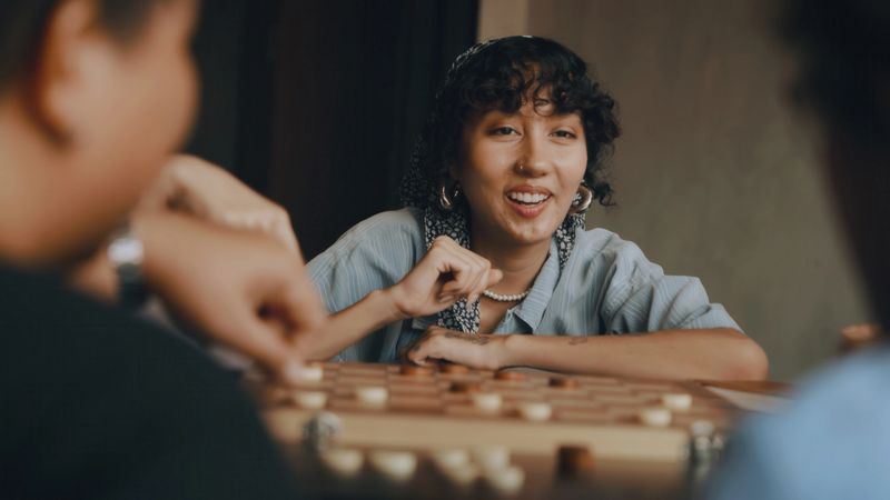 Diverse Group of Gen z Friends Enjoying a Board Game in a hostel