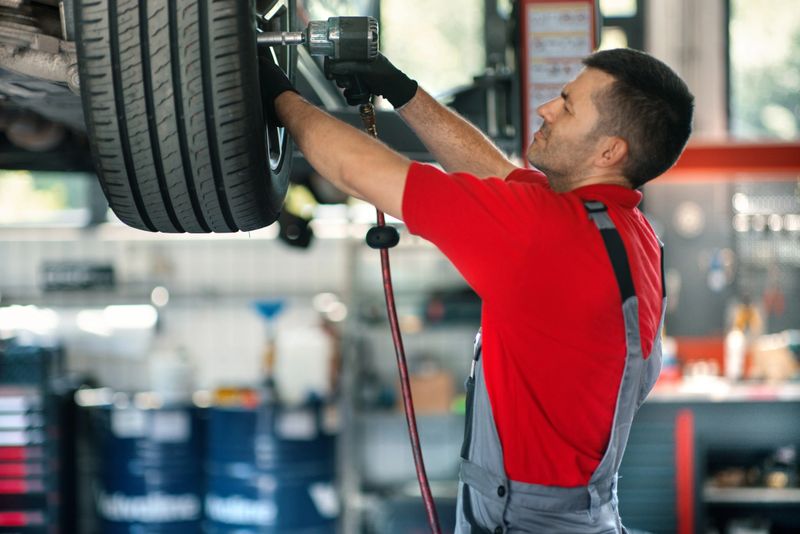 Closeup of a 40's male care mechanic replacing a tire at a car repair shop