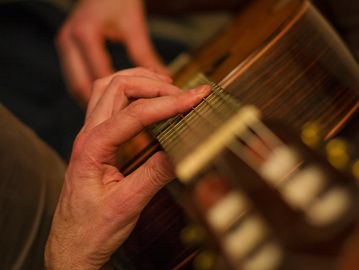 Close-up of hands playing acoustic guitar strings.