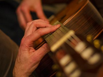 Close-up of hands playing acoustic guitar strings.