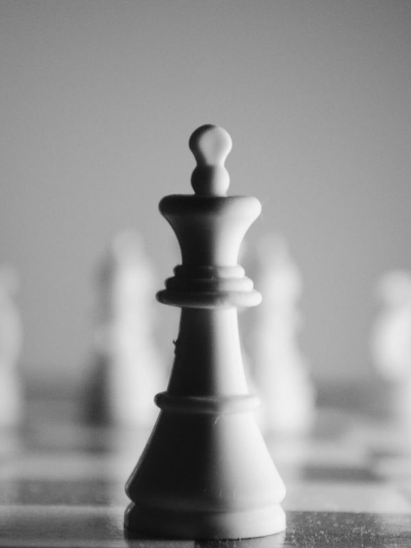 Close-up of a white king chess piece with blurred pieces in the background.