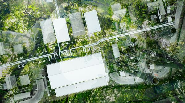 Aerial view of a factory complex surrounded by trees and greenery.