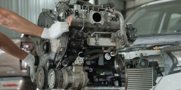 Mechanic handling a car engine in a garage.