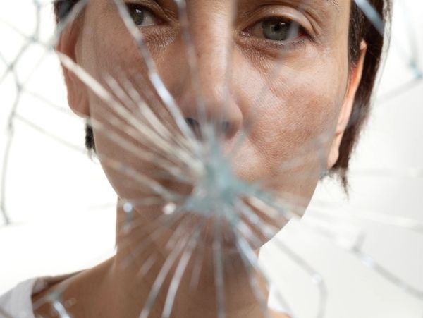 A person looking through a shattered glass mirror.