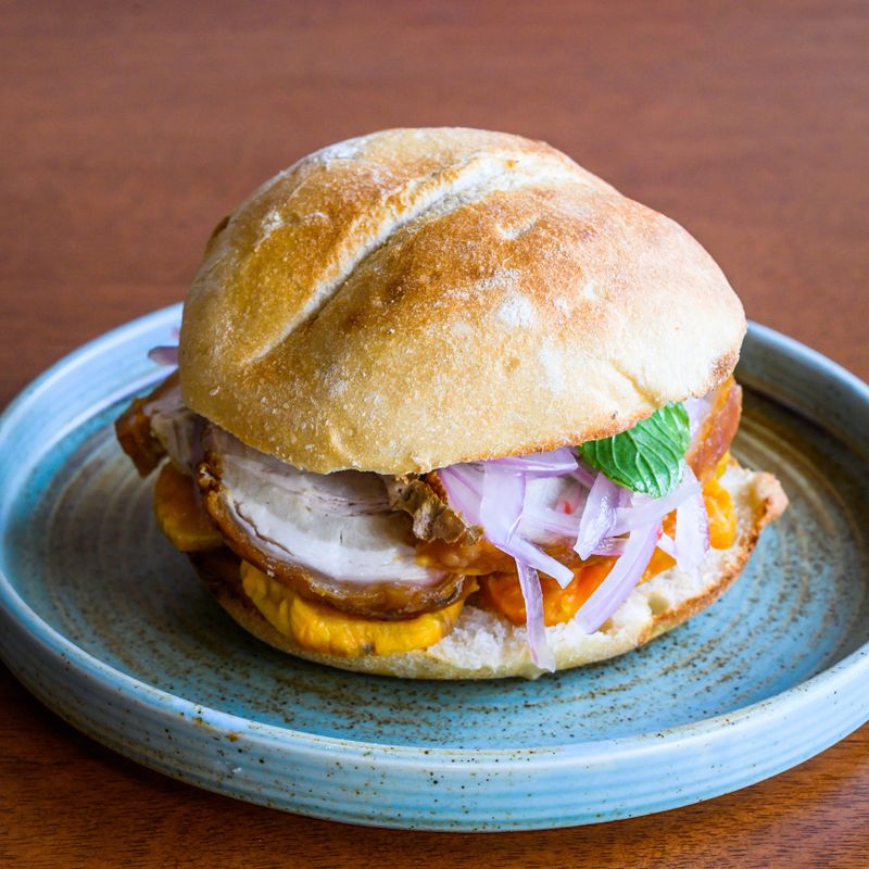 Tasty bread with pork, sweet potato, red onion, and criolla sauce, served on a plate