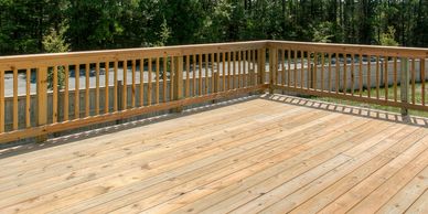 Empty wooden deck with railing on a sunny day.