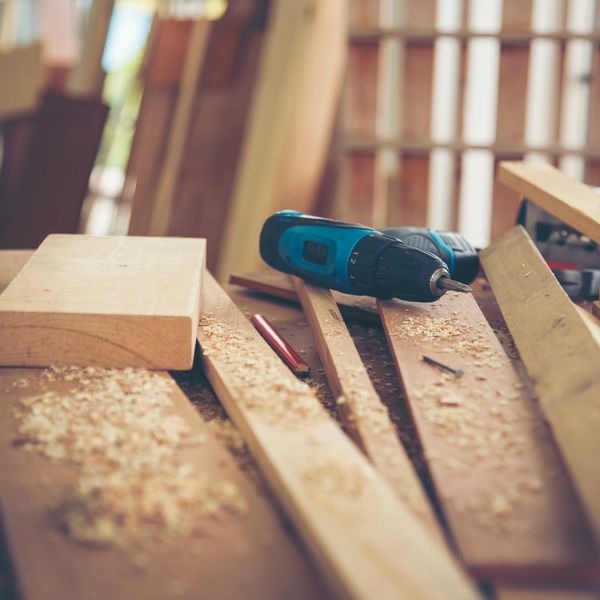 Cordless drill and wooden planks on a workbench.
