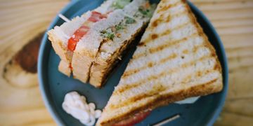 Grilled sandwich with tomato and vegetable filling on a blue plate.