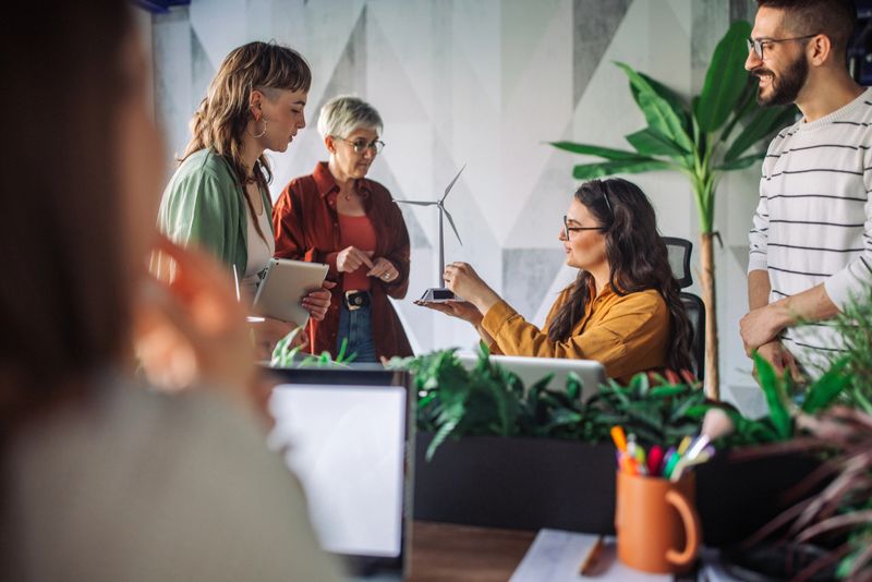 An innovative team immersed in discussing an energy model project at their office, fostering creativity and teamwork in an eco-friendly and modern workspace.